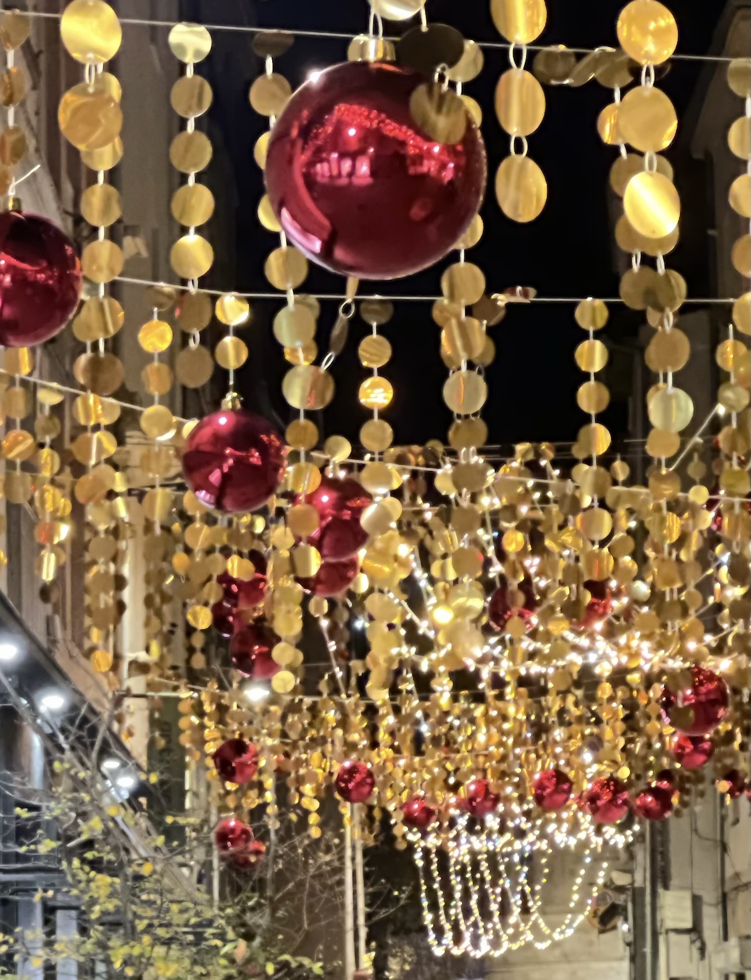 festive red and gold decorations hung across a pedestrian "passage", shot at night